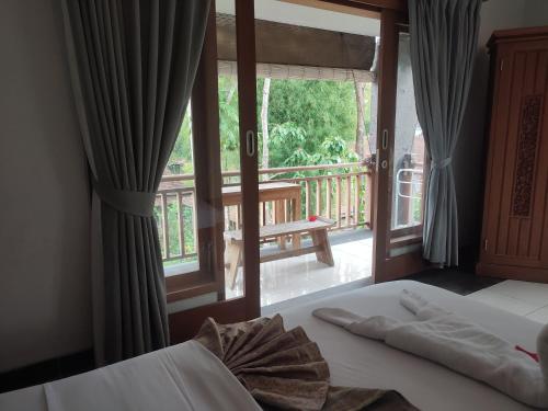 - une chambre avec un lit et une fenêtre avec un balcon dans l'établissement Nyoman Homestay Ubud, à Ubud