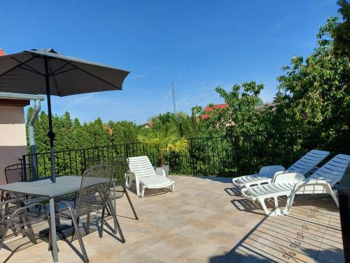 een patio met stoelen, een tafel en een parasol bij Violetta Vendégház in Keszthely