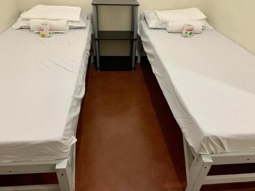 two beds in a room with white sheets at Mybed Dormitory in Cebu City