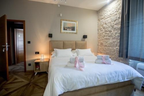 a bedroom with a large white bed with two pink pillows at St. Nicholas lighthouse - island of Brač in Pučišća
