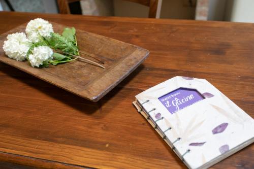 a table with a plate with a bouquet of flowers and a book at Agriturismo Poggio Salvi in Sovicille