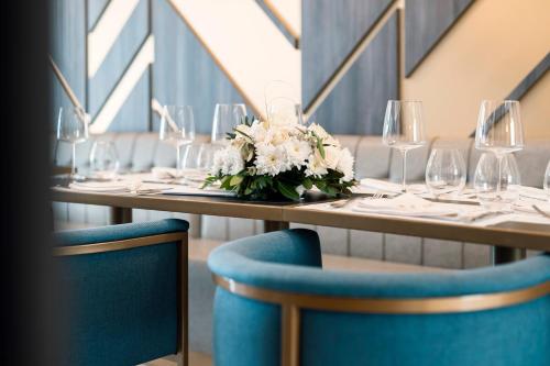 a table with plates and glasses and a bouquet of flowers at Hotel Millennium by Aycon in Budva