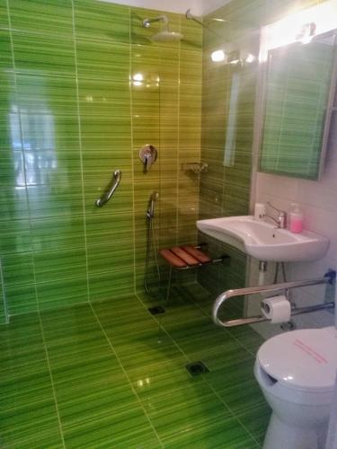 a green bathroom with a shower and a sink at Stratos Hotel in Afitos