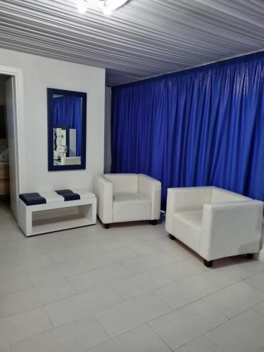a living room with two white couches and blue curtains at B&B Laura in Terzigno