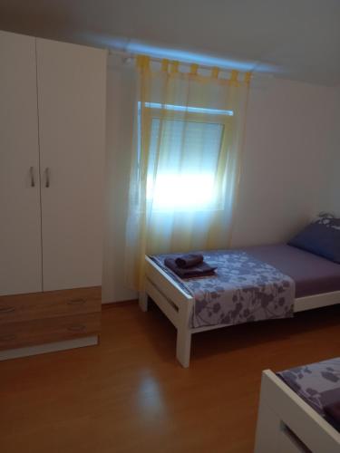 a small bedroom with a bed and a window at Apartments Dvorski in Mandre