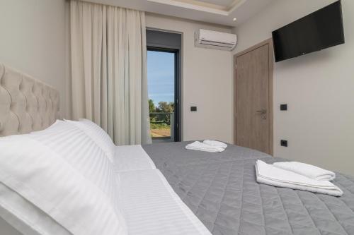 a bedroom with two white beds and a television at Royal View Villa - Private Pool & Hot Tub in Zakynthos Town