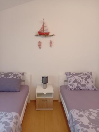 a room with two beds and a nightstand between them at Apartments Dvorski in Mandre