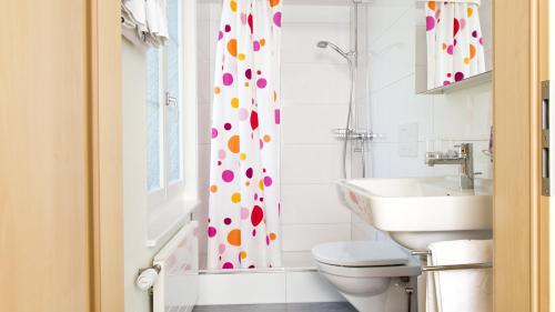 a bathroom with a toilet and a shower curtain with polka dots at Gasthof Rössli Gondiswil in Gondiswil