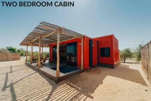 a small red building with a roof in the desert at Bab Al Nojoum Al Mugheirah in Al Mirfa