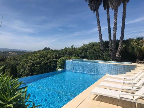 - une piscine avec des chaises blanches et des palmiers dans l'établissement Golfvilla Riviera, à Grimaud
