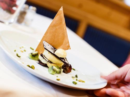 a person holding a plate with a dessert on it at Hotel Finkennest - Panoramic Garden Resort in Schenna