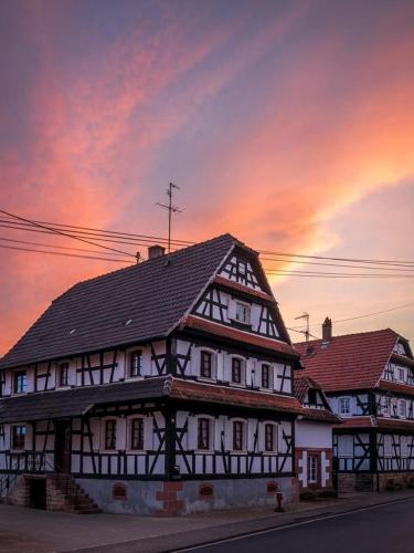 a white building with a black roof with a sunset at Quartier vert in Hunspach