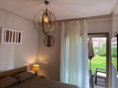 una camera da letto con un letto e un lampadario di Appartement de Luxe -Prestigia Marrakech Golf City a Marrakech