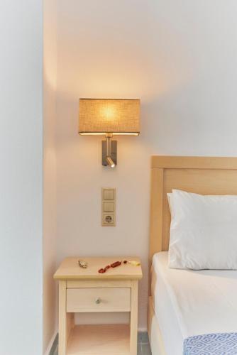 a bedroom with a bed and a nightstand with a lamp at Veneto Sea View Apartments in Stalida