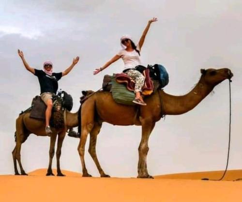 two people riding on the back of a camel at desert camp sahara luxury in Merzouga