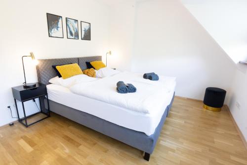 1 dormitorio con 1 cama con sábanas blancas y almohadas amarillas en Lahn-Living III - modernes und helles Apartment mit Top Ausstattung en Lahnstein