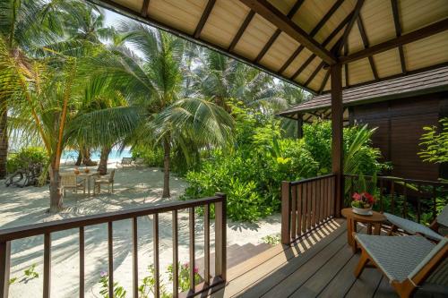 a wooden deck with a table and chairs on a beach at Fiyavalhu Resort Maldives in Mandhoo