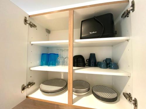 a cupboard with plates and a television in it at Le Bras d'or Apparts et Spa in Boulogne-sur-Mer