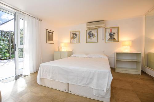a white bedroom with a bed and a window at BARKA in Mandre