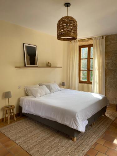 une chambre avec un grand lit blanc avec une fenêtre dans l'établissement Appartement de caractère à la Roque-Gageac, à La Roque-Gageac