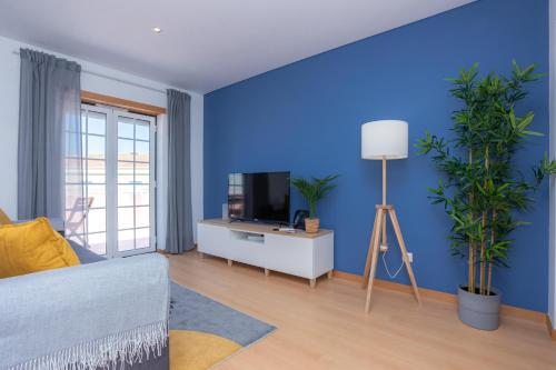 a blue living room with a couch and a tv at Terrace Bairro Novo by Rent4All in Figueira da Foz