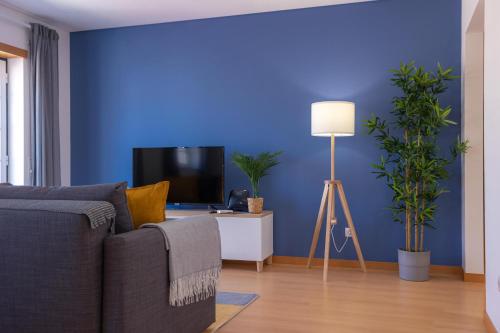 a blue living room with a couch and a tv at Terrace Bairro Novo by Rent4All in Figueira da Foz