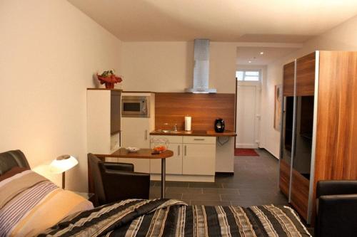 a room with a bed and a kitchen with a table at Campus Boardinghouse in Aachen
