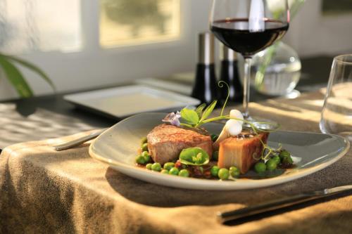 a plate of food on a table with a glass of wine at Hotel Le Lion D'Or et Restaurant La Table Du Lion in Bayeux