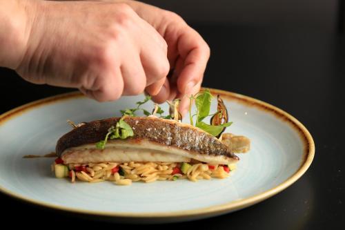 a person is holding a sandwich on a plate at Hotel Le Lion D'Or et Restaurant La Table Du Lion in Bayeux