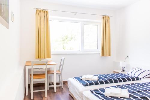 a bedroom with two beds and a desk and a window at Wesselényi Strand apartmanok in Balatonalmádi