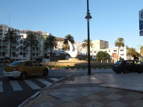 a street with cars parked in a city with buildings at La colombe appartement in Tétouan