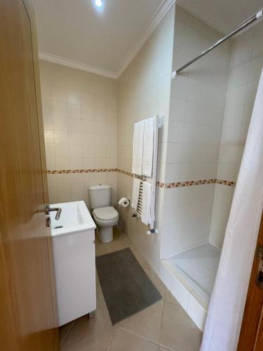a white bathroom with a toilet and a shower at Zulla Moradia T3, Praia do Norte in Nazaré