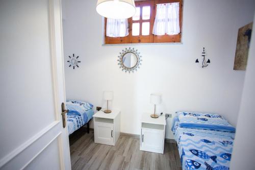 1 dormitorio con 2 camas, ventana y espejo en Casa Vacanze vista mare a Castellabate en Castellabate