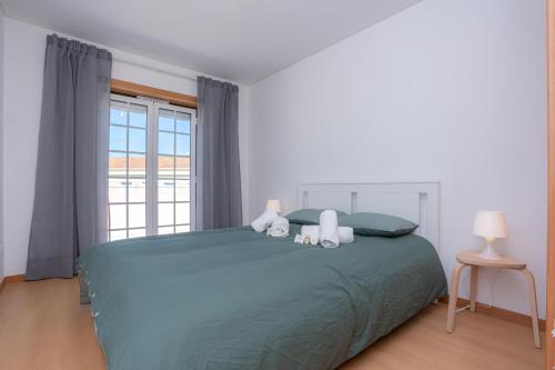 a bedroom with a large green bed with two pillows at Terrace Bairro Novo by Rent4All in Figueira da Foz