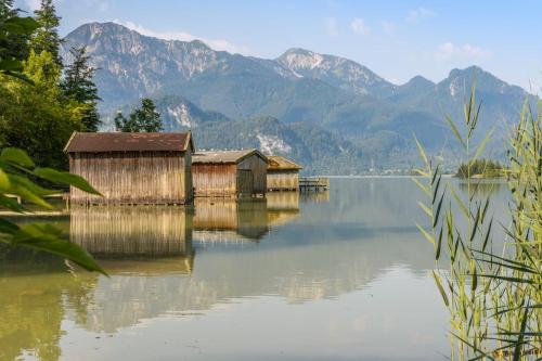 two buildings on the water with mountains in the background at Hotel Alpspitz B&B in Grainau