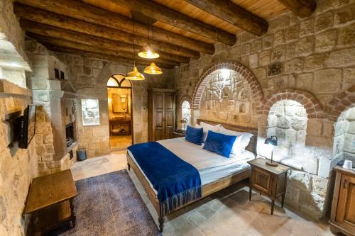 a bedroom with a bed and a stone wall at Ürgüp Cave Suites in Ürgüp