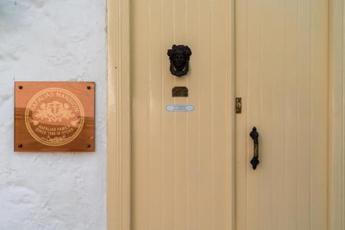 eine Tür mit einem Schild an der Wand in der Unterkunft Rafalias Mansion in Hydra
