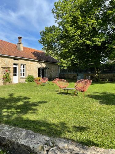 a group of chairs sitting in the grass in front of a house at La Closerie de Gigny Maison Templiere avec Piscine,jacuzzi in Gigny
