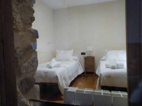a bedroom with two beds and a stone wall at Casa das Pozas in Distriz