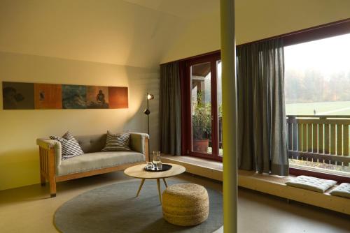 ein Wohnzimmer mit einem Sofa, einem Tisch und einem Fenster in der Unterkunft Hausteil in einer Waldlichtung im Stadtwald in Zürich