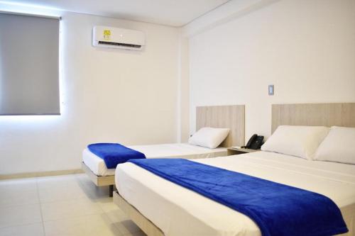 Habitación de hotel con 2 camas con sábanas azules en Hotel Blu Cúcuta, en Cúcuta