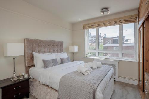 a bedroom with a large bed and a window at Perfect Location 2 Bed South Kensington Knightsbridge Chelsea with AC in London