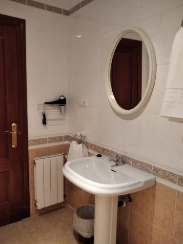 a bathroom with a white sink and a mirror at Pensión Vega de Pas in Comillas