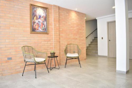 2 Stühle und ein Tisch neben einer Ziegelwand in der Unterkunft Hotel Blu Cúcuta in Cúcuta