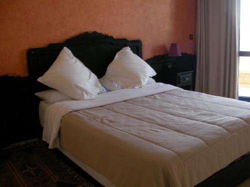Schlafzimmer mit einem Bett mit weißer Bettwäsche und Kissen in der Unterkunft Hotel Safa in Sidi Ifni