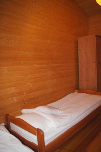 a bed in a room with a wooden wall at Domek letniskowy Barakuda in Chałupy