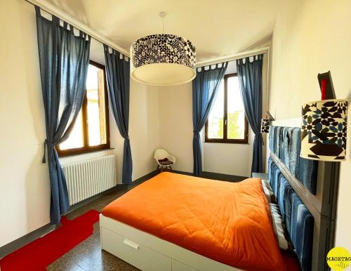 a bedroom with an orange bed and blue curtains at Piazza Arnolfo 1932 in Colle Val D'Elsa