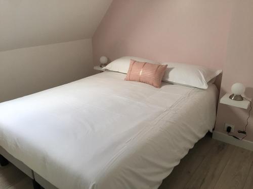 Una cama blanca grande con una almohada rosa. en Gîte La Fontaine en Mer