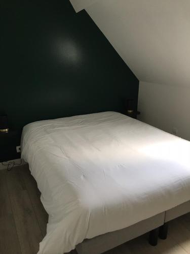 uma cama branca num quarto com uma parede verde em Gîte La Fontaine em Mer
