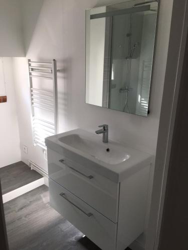 Baño blanco con lavabo y espejo en Gîte La Fontaine, en Mer